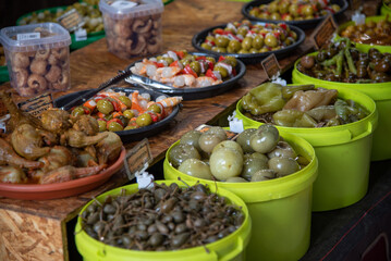 Detail of a street food market stall full of buckets and plates with olives of many kinds, spring onions, chillies and many typical products of Spanish gastronomy and the Mediterranean diet.