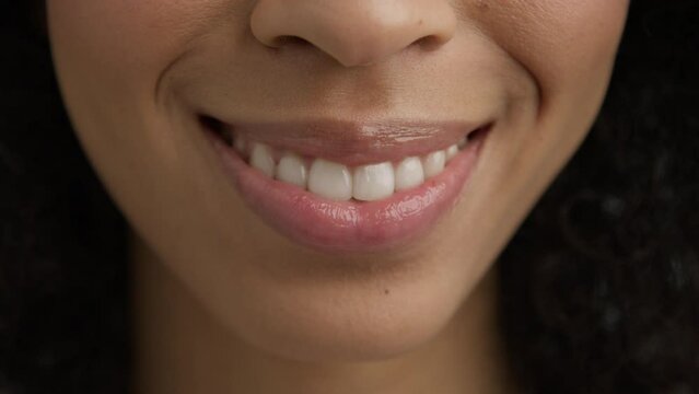 Woman mouth slow motion. Perfect soft skin sexy multi racial diverse model smiling kiss 4K. Lips kiss in natural day light. Beauty sexy female model with dark skin and full glossy pink lips closeup.