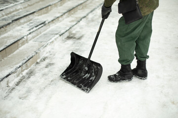 Snow shovel cleaning. Snow in yard in winter. Man cleans path from precipitation.