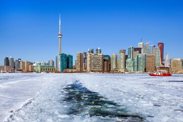 Toronto winter skyline with boat crossing the frozen bay