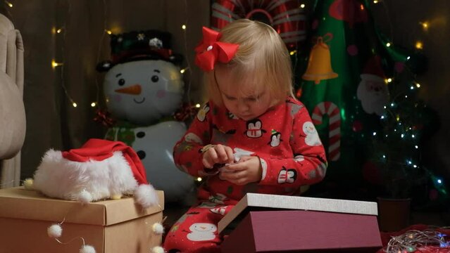 Cute two-year-old girl playing with Christmas gifts.