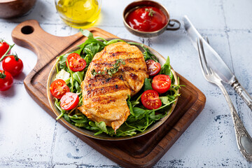 Grilled chicken breast with arugula and tomatoes on a plate