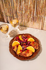 Christmas baked chicken with cranberries and oranges and two glasses of champagne on a festive modern table vertical photo