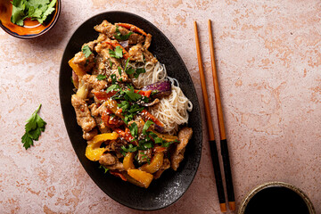 Asian pork with vegetables and funchose on a black plate top view