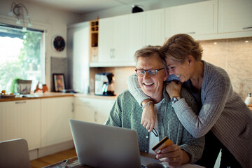 Middle aged couple holding credit card in the kitchen