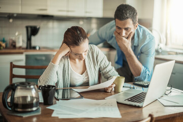 Upset couple paying bills or debt online on with a laptop at home