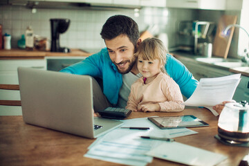 Young man holding document looking at laptop with daughter at home