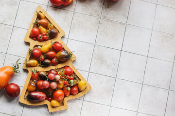organic ripe colorful tomatoes on a wooden board in the shape of a Christmas tree on the table