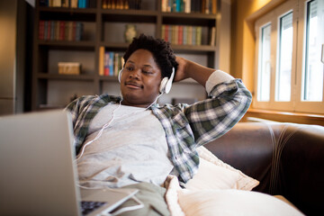 Young man with headphones using laptop in living room