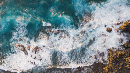 Atlantic ocean with strong swell beating against the walls of a rocky cliff, blue rough sea with...