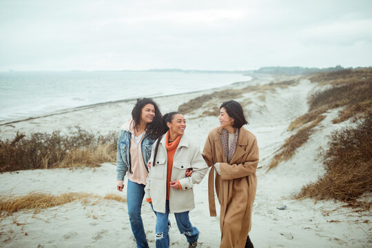 Three young women walking on cold beach together