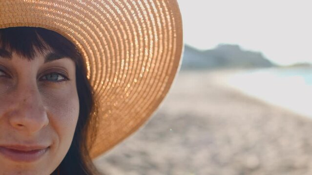 young girl on the beach. Portrait of a beautiful young woman in a straw hat on the seashore. Happy girl with black hair enjoying the sun.