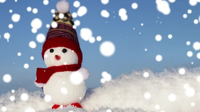 A snowman toy on the snow in a snowfall. Christmas, winter