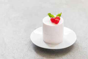 Red currant Panna Cotta cylindrical shape, on a plate. Light gray background. Copy space	