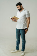 Young indian man standing with note book, isolated on white