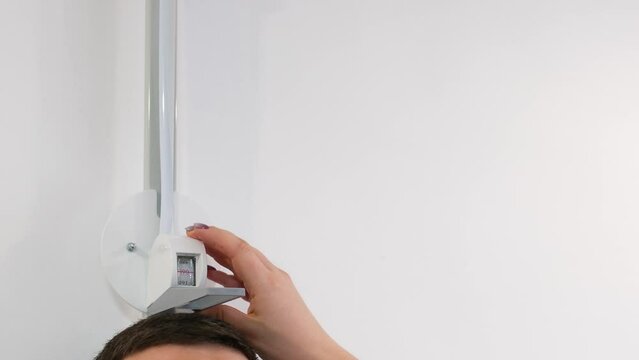 in the clinic with a professional stadiometer, the doctor measures the height of a dark-voiced man unrecognizable people measure the height of a persons height close-up space for text 