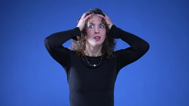 Anxious apprehensive woman reacting with shock and despair to news by putting arms on top of head and covering mouth in disbelief and surprise
