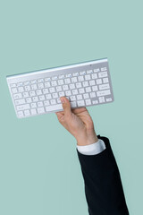 Hand holding wireless keyboard on isolated background for start up tech company. Eco-friendly green business promoting electronic waste policy idea. Quaint