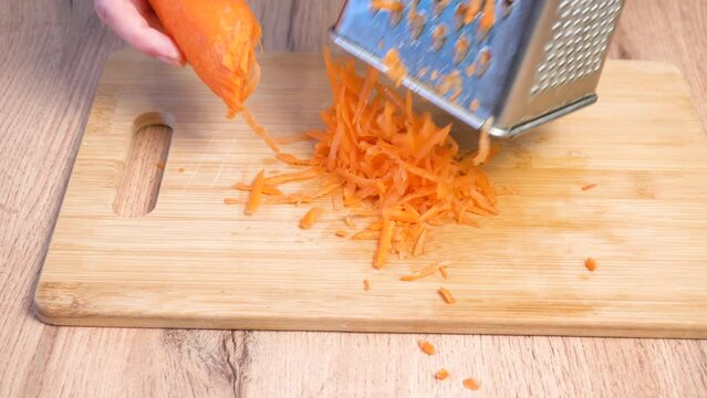 Grating carrots is shown in close-up. Cooking master class. Home cooking.