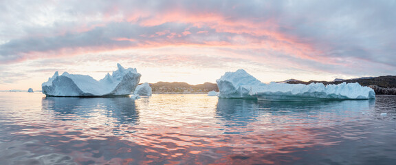 Arctic nature landscape with icebergs in Greenland icefjord with midnight sun. Early morning summer alpenglow during midnight season. Hidden Danger and Global Warming Concept. Tip of the iceberg.