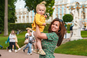 A young mother and child walk in the park with the Catherine Palace in Tsarskoye Selo in St....