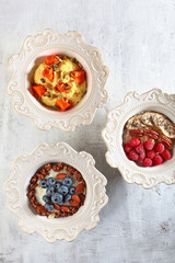 Set of bowls with porridge and berries in assortment on light background. Flat lay. Top view. Healthy food.