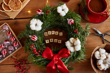 winter holidays, diy and hobby concept - close up of merry christmas greeting made of toy block or stamps, wreath making stuff and decorations on wooden boards