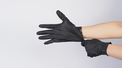  Hand is pulling black latex gloves on white background.