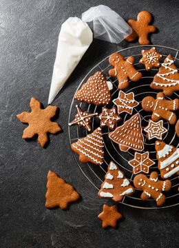 baking, cooking, christmas and food concept - close up of iced gingerbread cookies and pastry bag on black table top