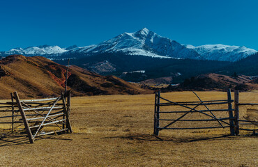 Fototapeta premium Pasture area with wooden fence on mountains background