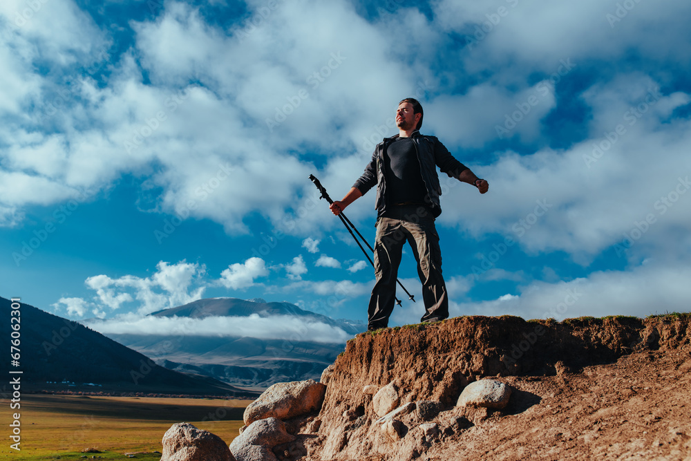 Canvas Prints Successful man tourist standing on top of mountain with trekking poles