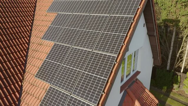 Modern photovoltaic monocrystalline solar cells made of solid silicon crystal with high efficiency of converting sunlight into electricity are installed on the tiled roof of a private house.