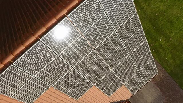Solar glare on photovoltaic monocrystalline solar modules made of a single silicon crystal, with increased efficiency of converting sunlight into electric current on the tiled roof of the house.