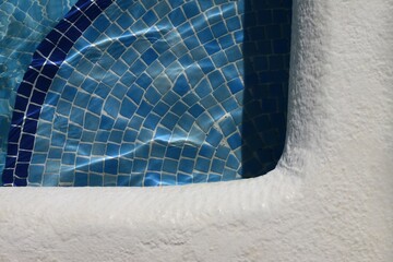 bode de piscina con gresite azul para fondo reflejados por el agua.
