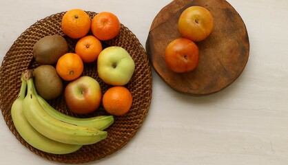 frutas variadas sobre plato de mimbre y tabla de madera.