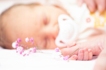 Limited focus sprig of delicate gypsophila flower with baby sleeping in background and holding...
