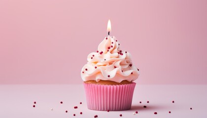 Deliciously decorated single birthday cupcake with pink candle on a light pink background