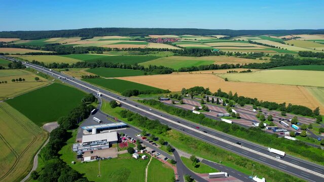 Aerial flyover above the Autobahn highway and truck stop rest area during summer in Germany