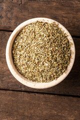 Dried marjoram leaves in bowl on wooden table. Close up. Top view