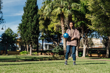 Fototapeta premium A beautiful brunette girl holds a blue rubber ball in her hands
