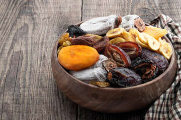 Dried fruits in wooden bowl on rustic wooden table