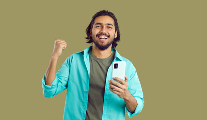 Happy Indian man with mobile phone in his hands rejoices at good news or winning. Happy excited...