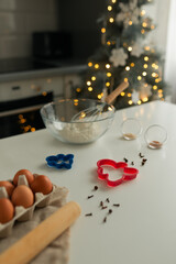 On the kitchen table there is a bowl with flour, a whisk, spices and molds for making Christmas cookies