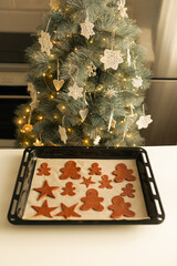 Cut out Christmas cookie dough shapes on a baking sheet.