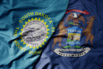big waving colorful national flag of michigan state and flag of south dakota state .