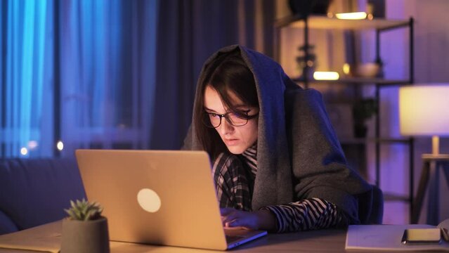 Anxious paranoid young woman nervously typing on a laptop scrolling through news or social media feed looking around so that no one is spying at late night at home workplace Addiction concept