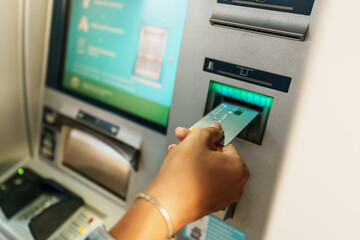 In a tightly framed shot, the woman's hands are shown while she inserts her card into the ATM and...