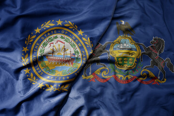 big waving colorful national flag of pennsylvania state and flag of new hampshire state .