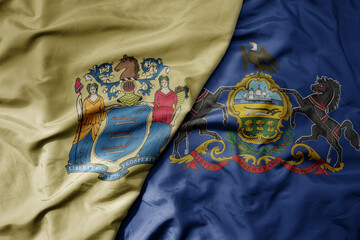 big waving colorful national flag of pennsylvania state and flag of new jersey state .