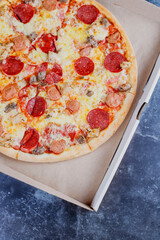 Hot tasty traditional various italian pizzas with salami, meat, cheese, onion, mushroom, tomatoes greens on a dark background